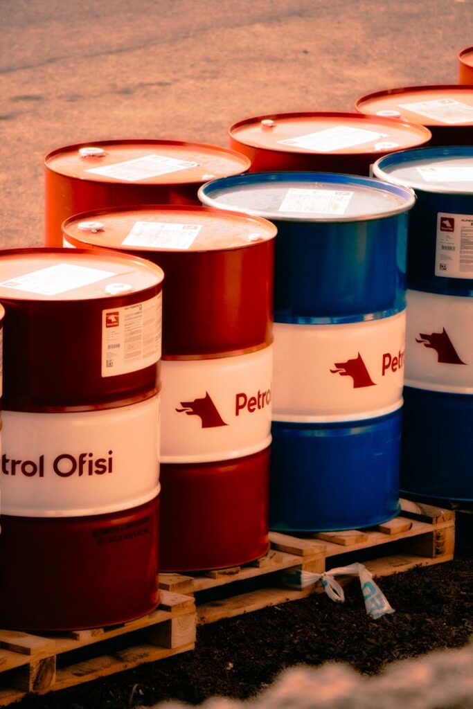 A collection of red and blue oil barrels labeled 'Petrol Ofisi' in an outdoor industrial setting in Turkey.