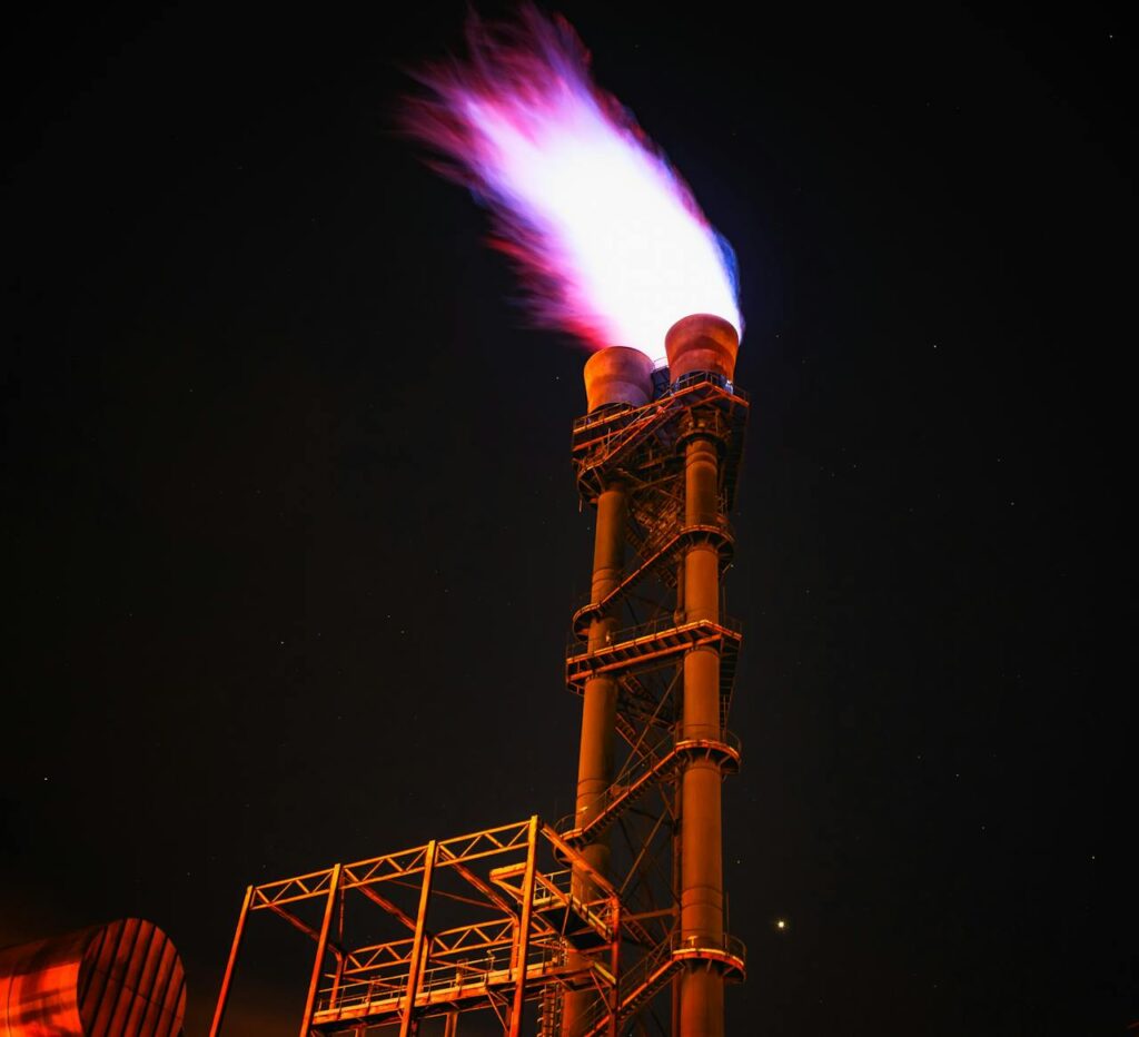 Dramatic night photo of gas flare on industrial facility emitting a powerful flame.